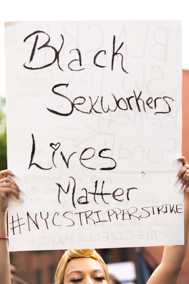 Brooklyn Liberation attendant holding a white poster with "Black Sexworkers Lives Matter #NYCSTRIPPE...