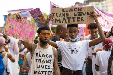 Two men wearing "Black Trans Lives" t-shirts and holding posters with same signs