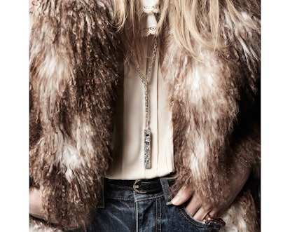 A model wearing a white shirt, blue denim jeans, and a beige fur coat by Celine