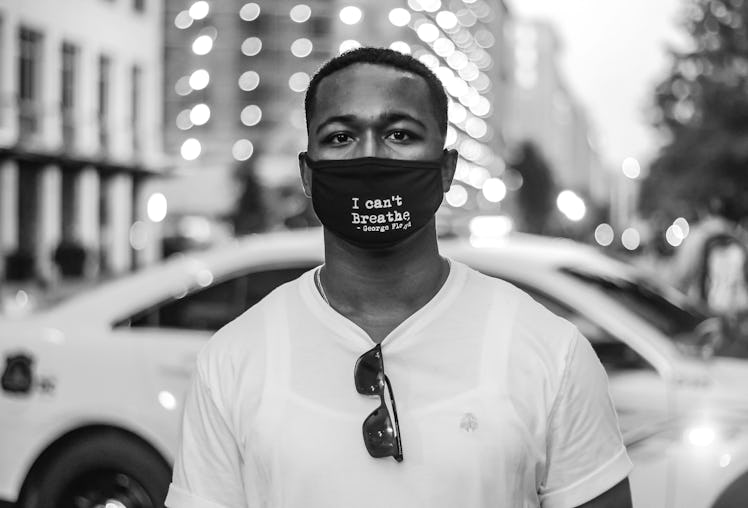 Solomon standing in front of a Police car with a face mask with George Floyd’s last words.
