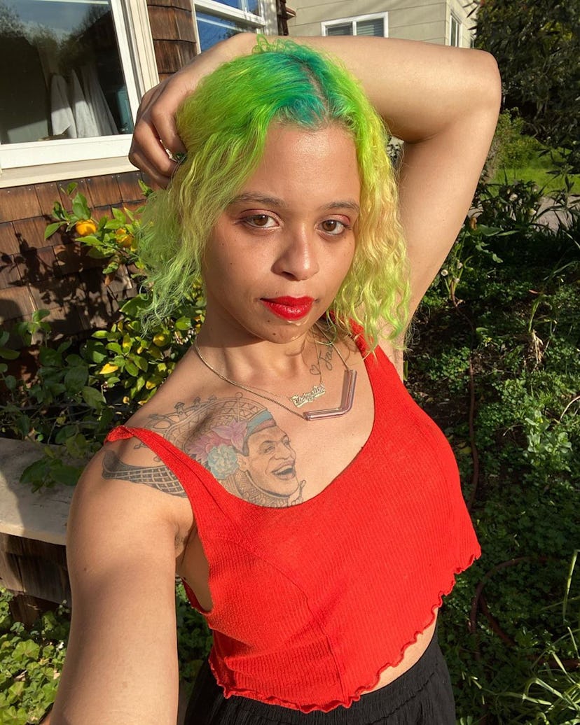 Tourmaline posing for a photo in a red cropped tank and black pants