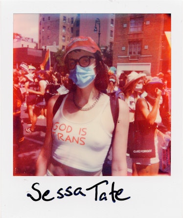 A person in a polaroid shot at the New York City Pride March in a top with the text 'GOD IS TRANS' a...