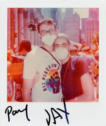 A polaroid shot of two people posing and hugging at the New York City Pride March with the text 'Pad...