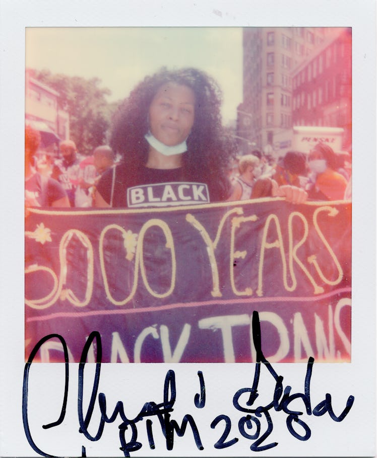 A polaroid shot of a person holding a poster '6000 years Black Trans' at the New York City Pride Mar...