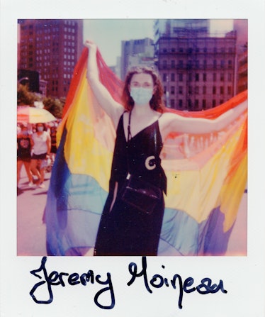 A person in a polaroid shot holding the LGBTQ+ flag at the New York City Pride March and the text 'J...