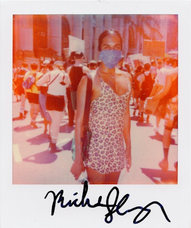 A polaroid shot of a person in a floral dress and a blue bandana on their face at the New York City ...