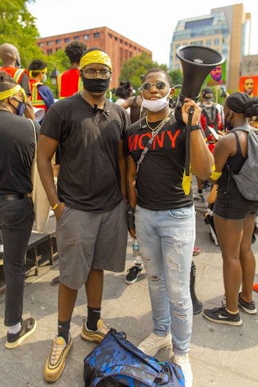 Two activists in black shirts with a white and a black face mask on the 4th of July