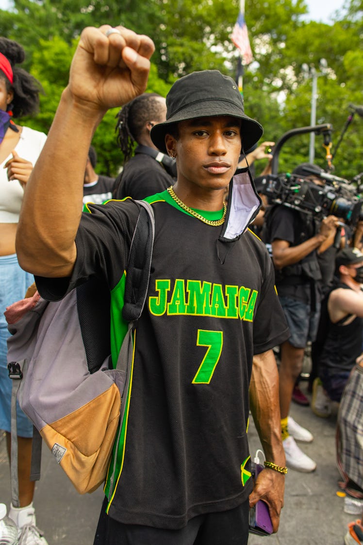 A man in a black T-shirt and bucket hat with one arm raised on the 4th of July