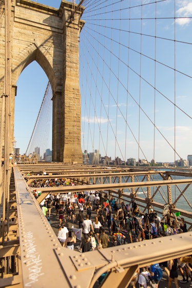 A semi-aerial view of the Brooklyn Bridge and protesters walking on it on the 4th of July