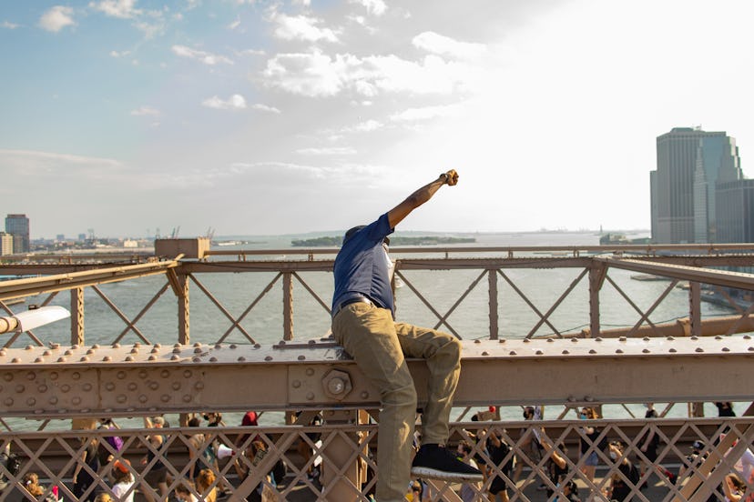 A man sitting with his arms stretched out on a metal construction of a bridge in 2020