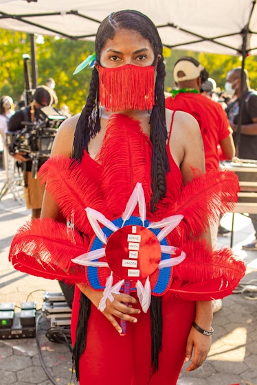 A woman in a red dress, red fringed face mask and a red-blue-white headpiece on the 4th of July