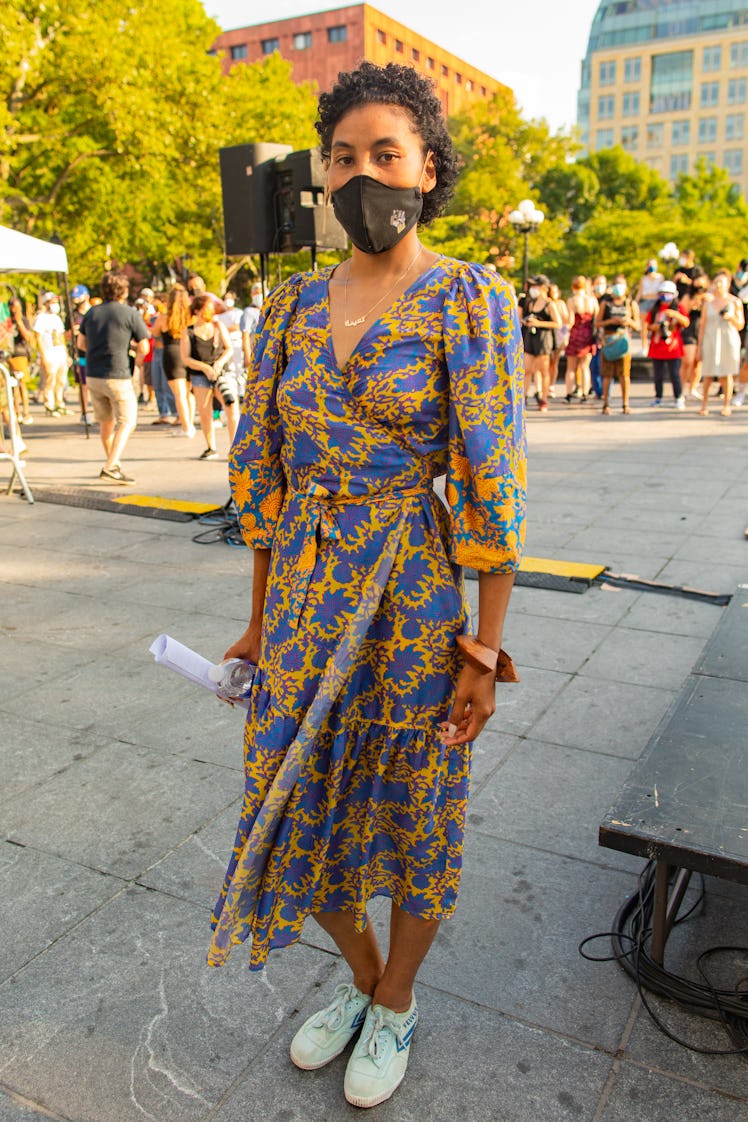 A woman in a blue-yellow floral dress and a black face mask on the 4th of July