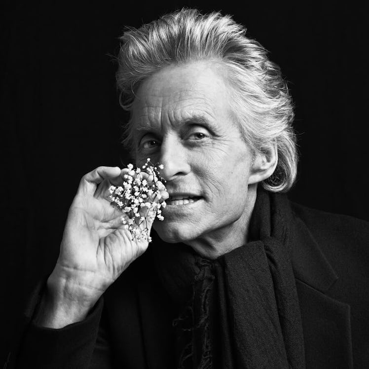 Michael Douglas, star of The Kominsky Method, posing for a photo while holding a tiny white branch w...
