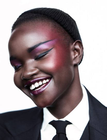 A smiling woman posing in a white shirt, black tie, and black blazer while having Black-Owned Beauty...