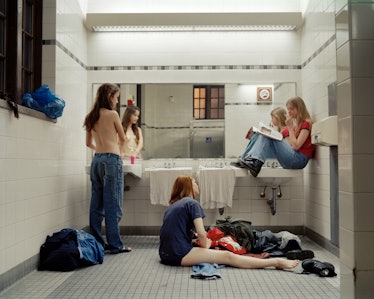 Topless woman standing in front of a mirror in the restroom