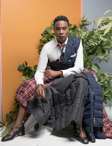 Billy Porter posing while wearing a white shirt, red plaid skirt, and black heels
