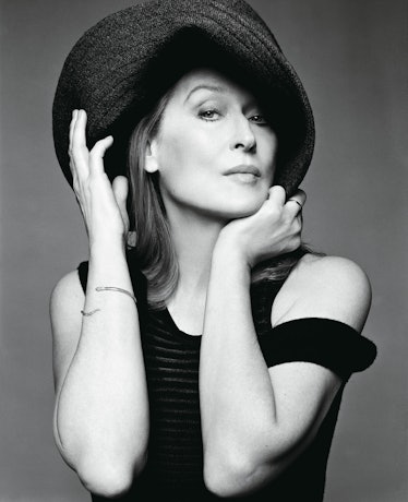 Meryl Streep posing for a photo while wearing a black dress and a black hat