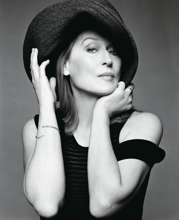 Meryl Streep posing for a photo while wearing a black dress and a black hat