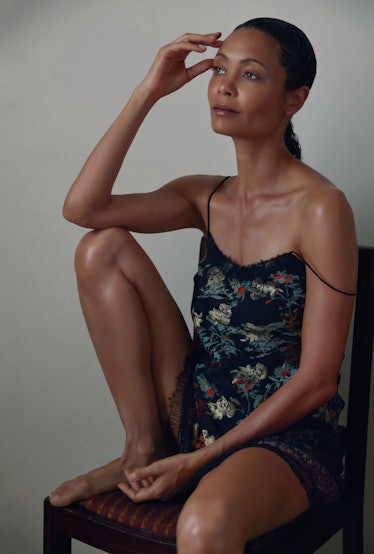 Thandie Newton sitting while wearing a black mini dress with light blue and green flower drawings on...