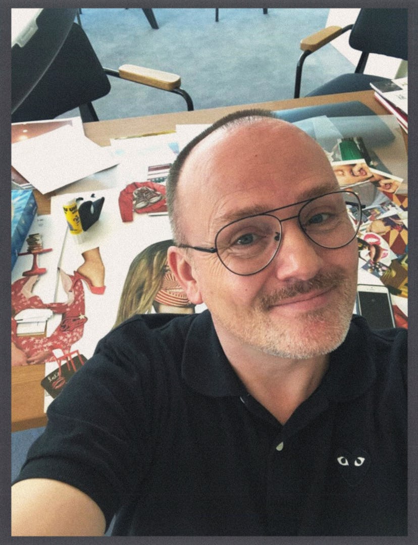 Peter Philips taking a selfie with his collages on a table in the background
