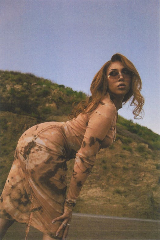 Kali Uchis posing for a photo in a brown dress