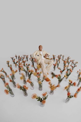 A photograph by Micaiah Carter of Pharrell Williams in a room full of flowers in vases
