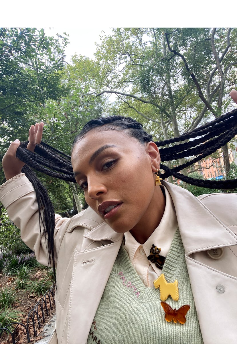 Paloma Elsesser posing for a photo while holding her black dreadlock hairstyle in her hands