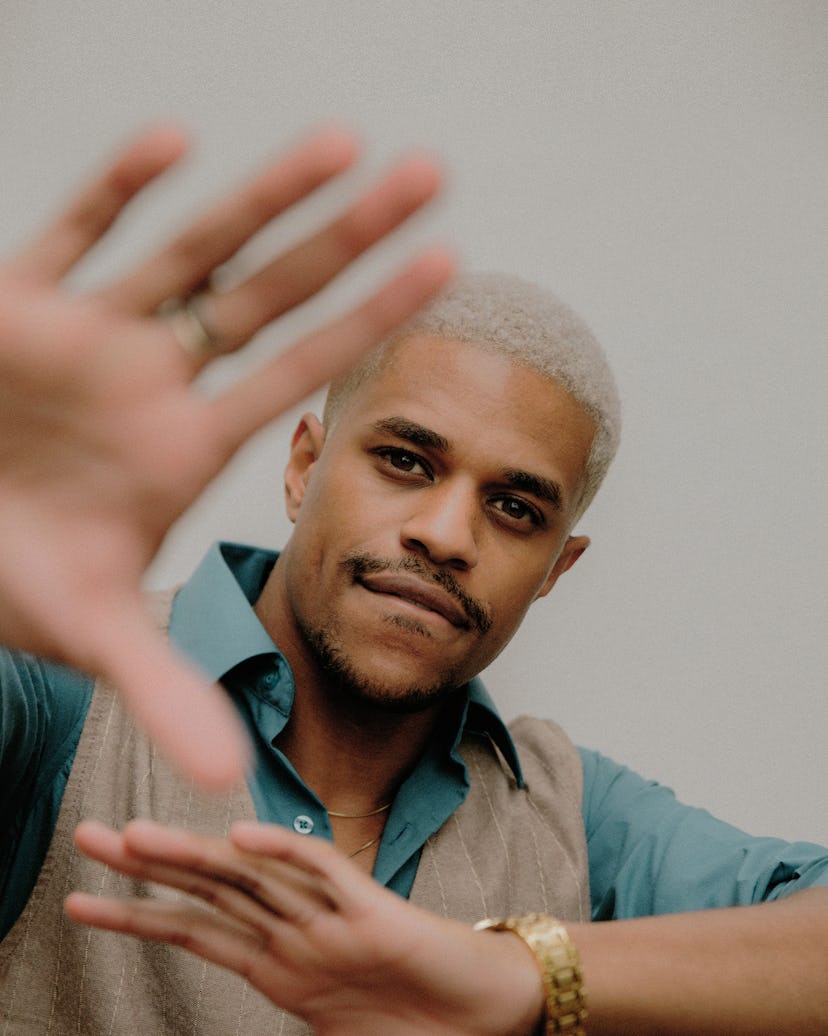A portrait of Jeremy Pope in a blue shirt and a beige knit waistcoat