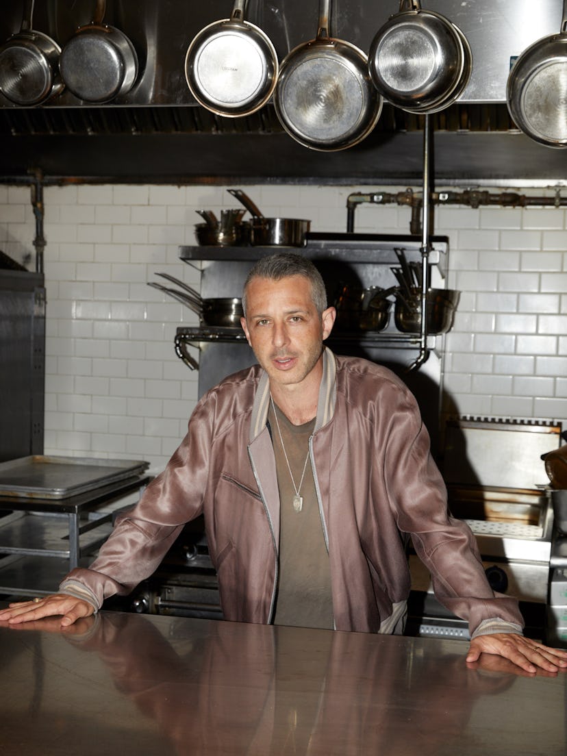 Succession’s Jeremy Strong in a khaki shirt and a mauve satin bomber jacket in a kitchen