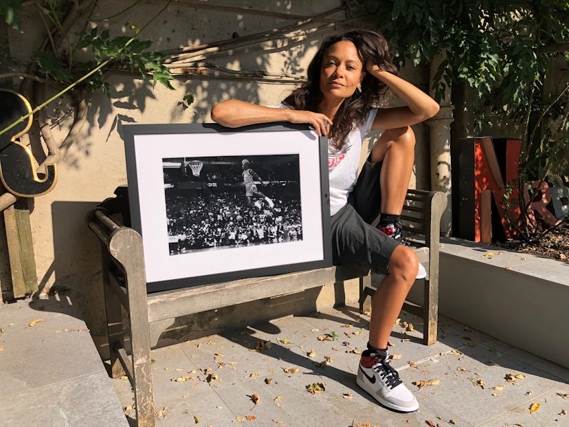 Thandie Newton sitting on a bench and posing next to a framed black-and-white photograph