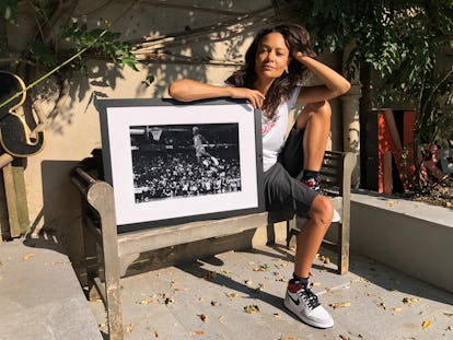 Thandie Newton sitting on a bench and posing next to a framed black-and-white photograph