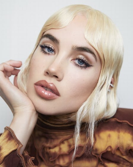 A blonde model in a brown shirt wearing Byredo’s Debut Makeup Line