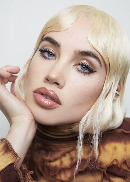 A blonde model in a brown shirt wearing Byredo’s Debut Makeup Line