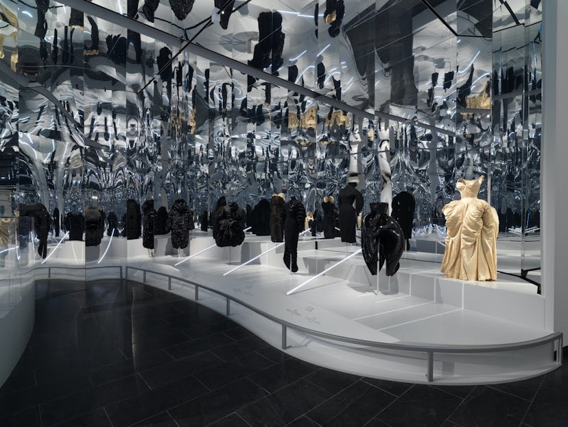An exhibition at the Met Gala, featuring black dresses and one gold dress