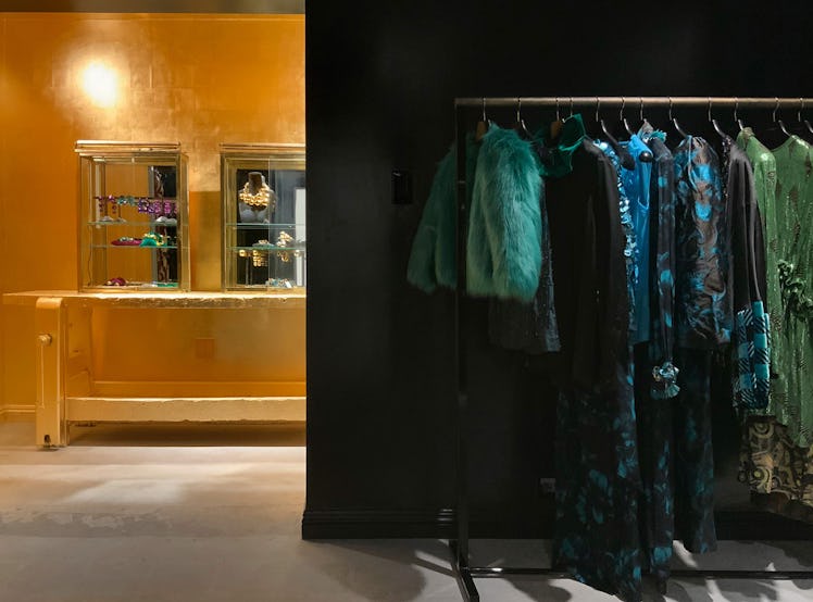 The inside of the Dries Van Noten store with clothes hanging on a rack and two box displays on a yel...