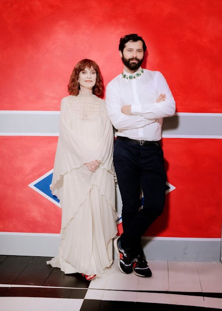 Gherardo Felloni in a dress shirt and pants and Isabelle Huppert in a beige gown posing leaned again...