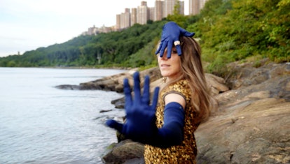 The ballet dancer Luciana Paris posing next to the sea wearing a golden dress and blue gloves
