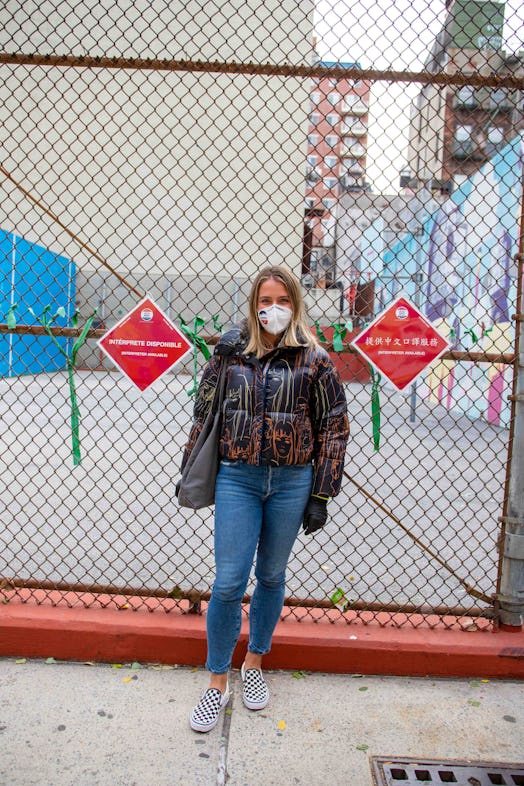 Chrissy Nichol, a first-time poll worker in a shiny puffer coat and white face mask, standing in fro...