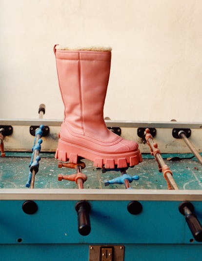A chic rugged pink Prada boots placed on top of a foosball table.