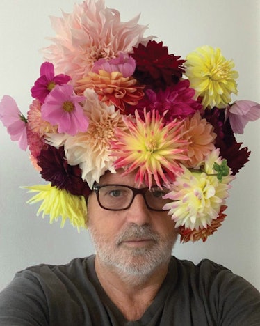Sam McKnight taking a selfie while having a flower bouquet wig on his head