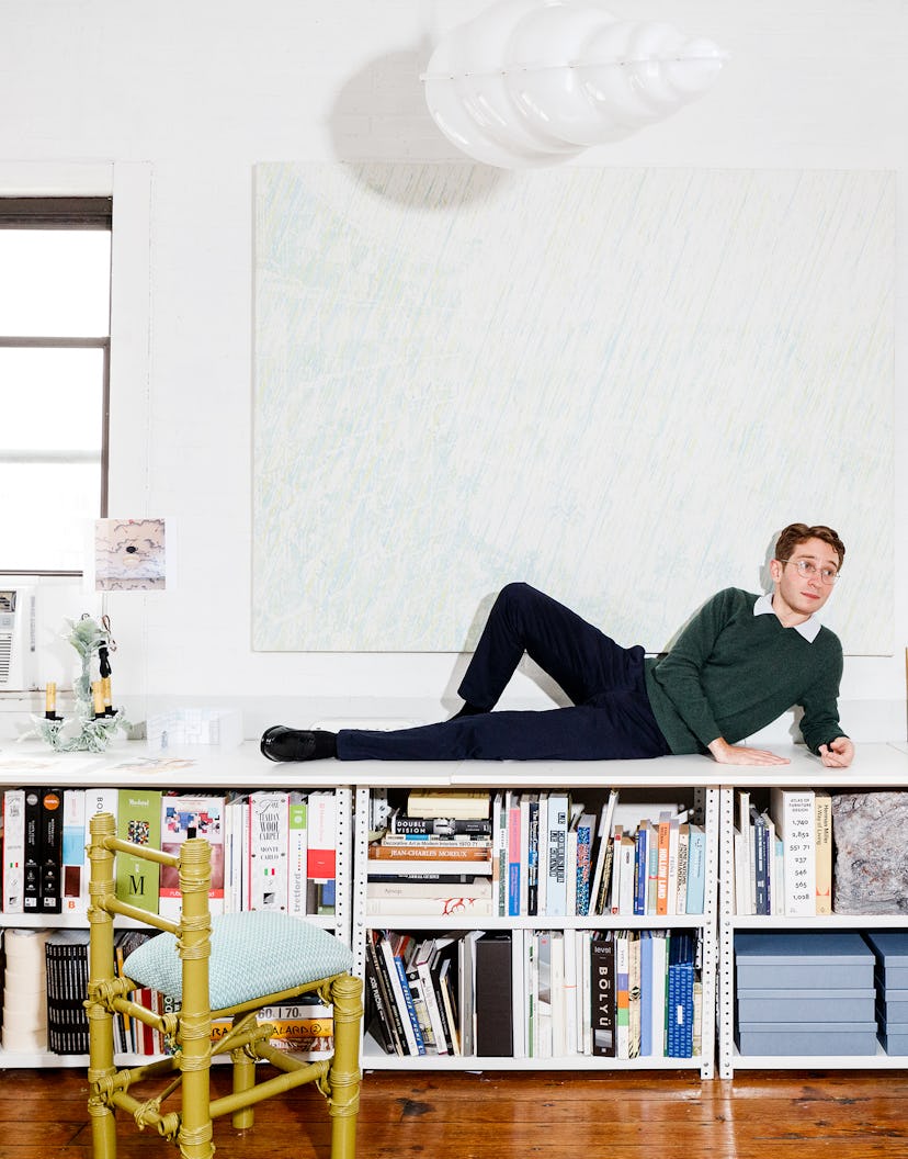 Architect Adam Charlap Hyman lying on a bookshelf in his studio