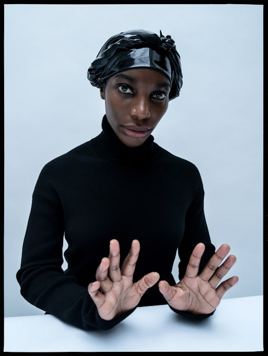 Michaela Coel wearing a black turtleneck sweater and a black nylon hat