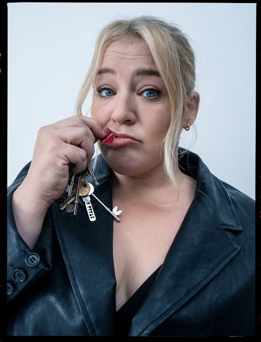 Harriet Webb in a black leather coat, holding keys and a keychain next to her mouth