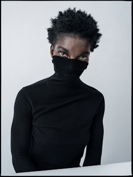 Michaela Coel in a black turtleneck with the collar over her mouth and nose