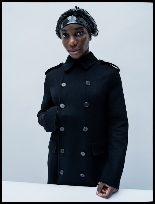 Michaela Coel in a black coat and black nylon hat