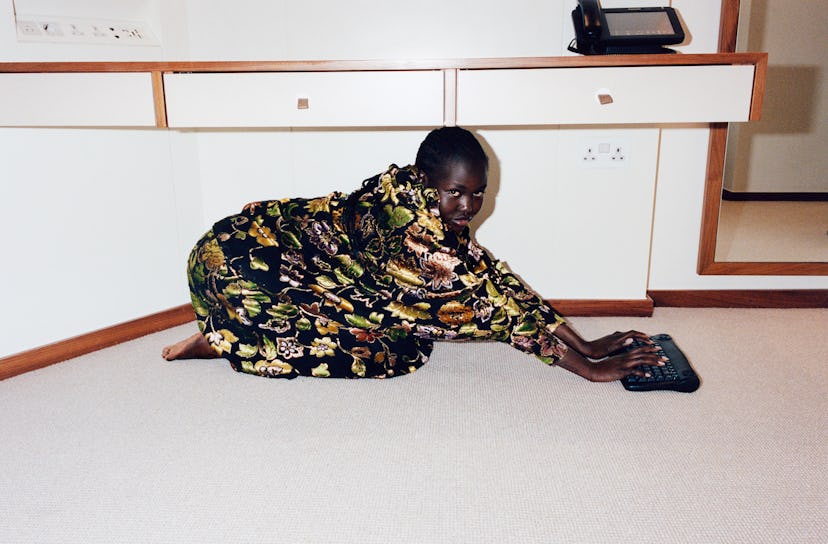 Model Adut Akech wearing a floral kimono while posing on her knees for a photo