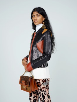 A model wearing a white shirt, black-brown leather jacket, floral pants and brown bag by Louis Vuitt...