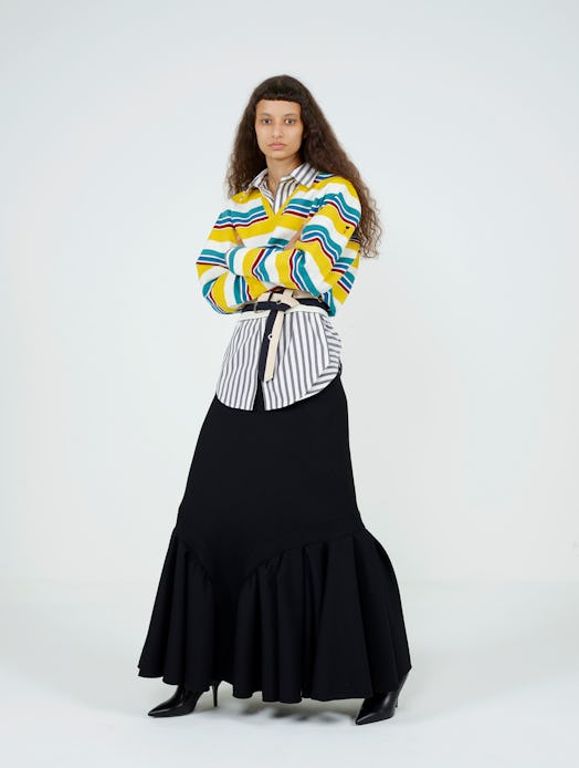 A model wearing a black-white striped shirt, blue-yellow cardigan and black skirt from Cruise 2021