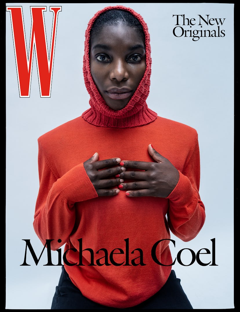 Michaela Coel posing in a red sweater, a red knitted hat, and black pants on the cover of W