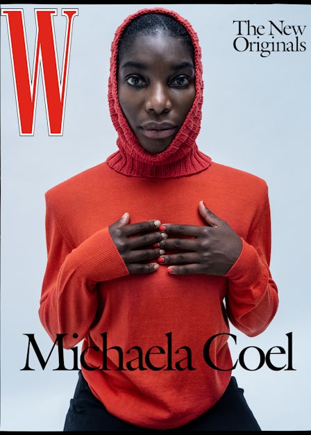 Michaela Coel posing in a red sweater, a red knitted hat, and black pants on the cover of W